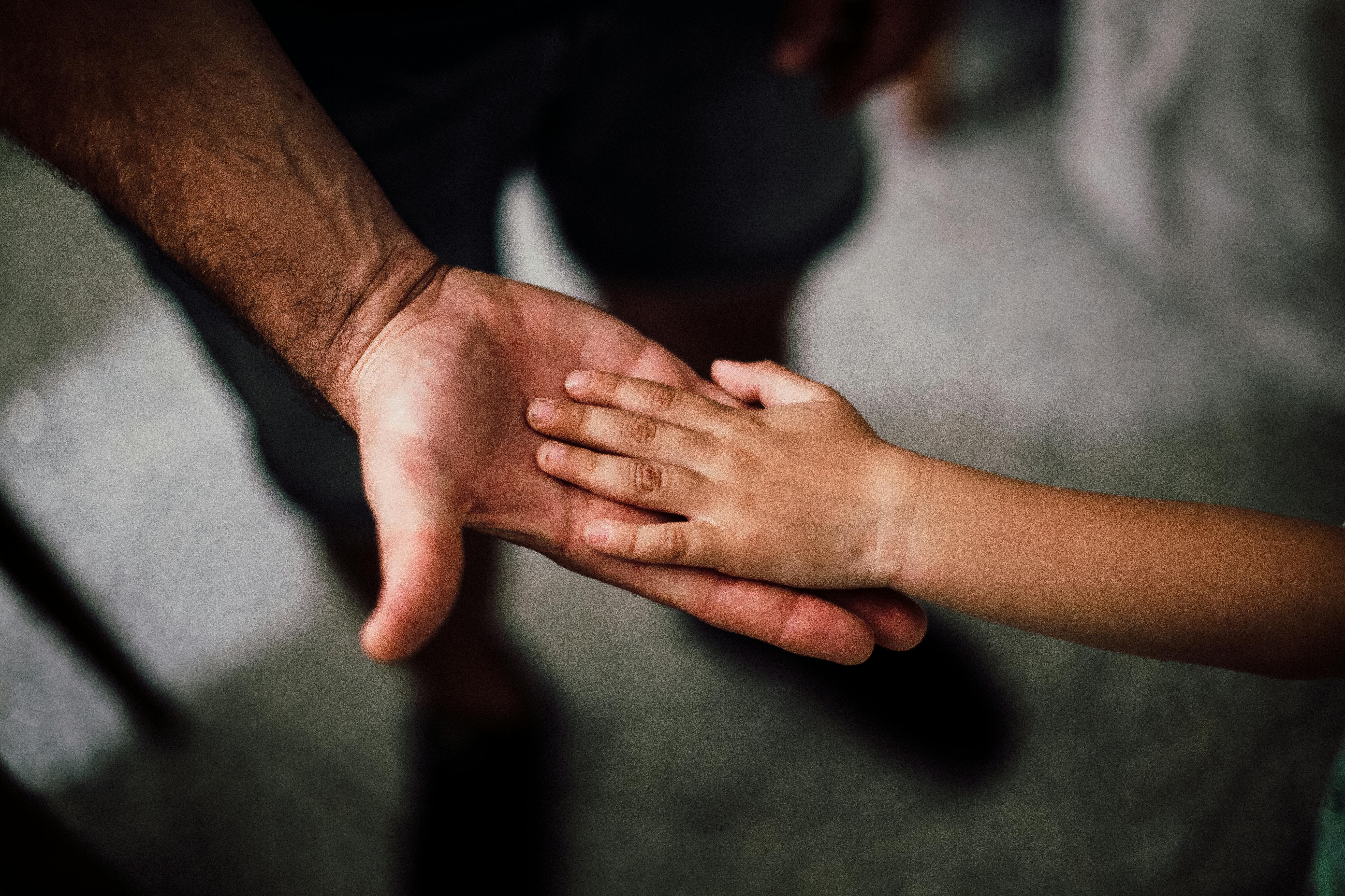 A child’s hand resting on an adult’s hand
